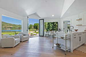 Kitchen featuring a sink, lofted ceiling, open shelves, white cabinets, and light countertops
