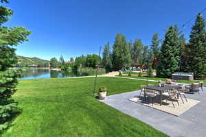 View of green lawn featuring a hot tub, a patio, and a water and mountain view