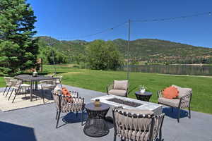 View of patio / terrace featuring an outdoor fire pit, a water and mountain view, and outdoor dining space