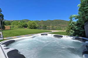 View of pool featuring a water and mountain view, a yard, and a hot tub