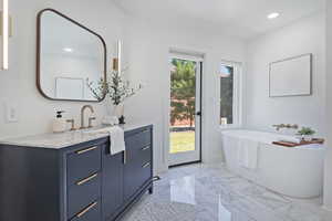 Full bathroom featuring recessed lighting, a freestanding bath, vanity, marble finish flooring, and baseboards