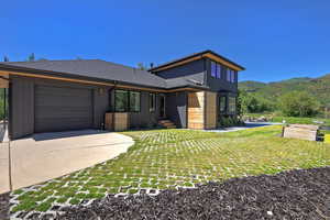 Modern home with driveway, an attached garage, a mountain view, and a front lawn
