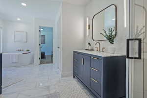 Full bathroom with a soaking tub, vanity, marble look tile flooring, baseboards, and recessed lighting