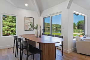Dining area featuring baseboards, hardwood / wood-style floors, a water view, and vaulted ceiling