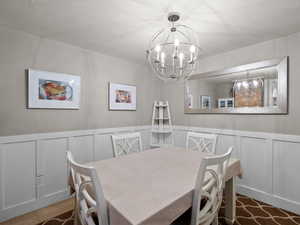 Dining room with a chandelier, a decorative wall, and wainscoting