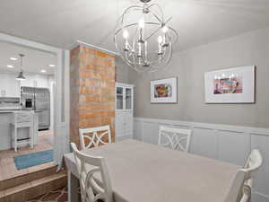 Dining room with a chandelier, a wainscoted wall, recessed lighting, and a decorative wall