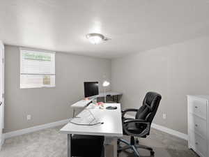 Office area featuring a textured ceiling, light carpet, and baseboards