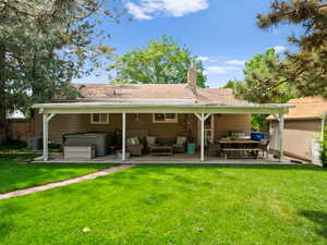 Rear view of property featuring a hot tub, a patio area, an outdoor hangout area, a chimney, and central AC unit