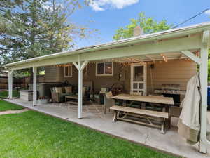 Rear view of property with a patio, a chimney, an outdoor living space, and a hot tub