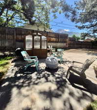 Fenced backyard featuring an exterior structure, a patio, an outdoor fire pit, and an outdoor structure