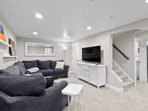 Living area with light colored carpet, recessed lighting, baseboards, and stairs