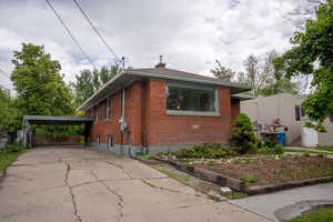 Bungalow-style home featuring brick siding, driveway, and a chimney, carport!