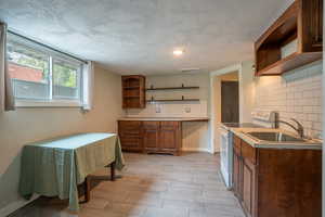 Kitchen featuring open shelves, white electric stove, a sink, and tasteful backsplash
