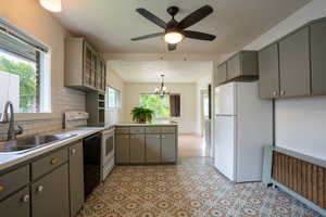 Kitchen featuring white appliances, gray cabinets, a sink, and a peninsula.  Tile floor and back splash !