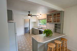 Kitchen featuring freestanding refrigerator, a sink, gray cabinetry, a peninsula, and baseboards new tile floor and back splash