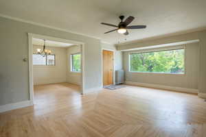 Unfurnished room featuring radiator heating unit, baseboards, a chandelier, a ceiling fan, and ornamental molding