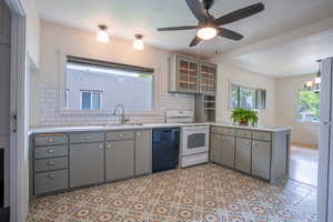 Kitchen with dishwasher, white range with electric cooktop, a sink, and gray cabinetry