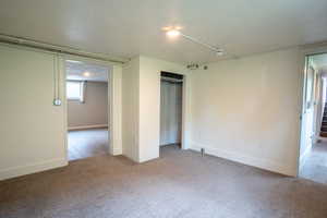 Unfurnished bedroom with carpet, a closet, and baseboards