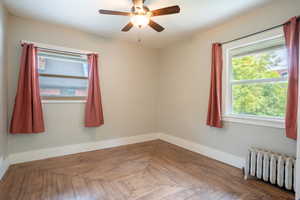 Spare room featuring radiator heating unit, baseboards, and ceiling fan