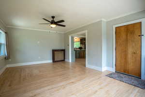 Unfurnished living room with ceiling fan, baseboards, and ornamental molding