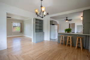 Unfurnished dining area with a chandelier, a ceiling fan, and baseboards
