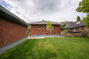 Rear view of property with a patio area, brick siding, and a lawn