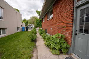 View of side of home featuring brick siding and a yard floral pathway to front of home