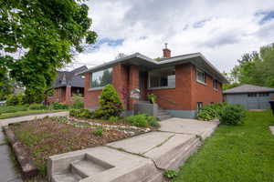View of front of house with brick siding, a chimney, and a front lawn