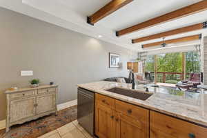 Kitchen featuring dishwasher, a sink, open floor plan, light stone countertops, and ceiling fan