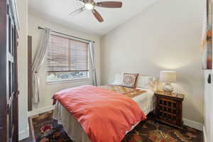 Bedroom with baseboards, vaulted ceiling, wood finished floors, and a ceiling fan