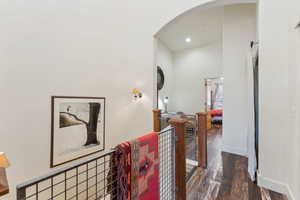 Hall with arched walkways, wood finished floors, baseboards, and recessed lighting