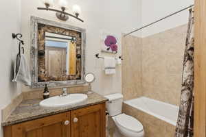 Bathroom featuring tiled shower / bath combo, toilet, and vanity
