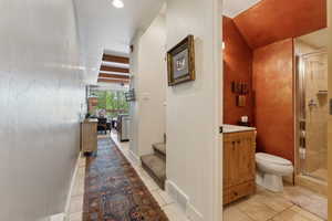 Bathroom with toilet, a stall shower, tile patterned flooring, and vanity