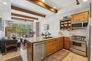 Kitchen with stainless steel appliances, a peninsula, tasteful backsplash, open floor plan, and a sink