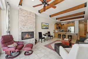 Living room with beam ceiling, a ceiling fan, a stone fireplace, recessed lighting, and light tile patterned floors