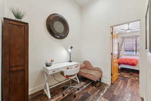 Office area with dark wood-style flooring, baseboards, and a ceiling fan