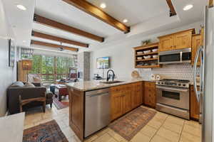 Kitchen with appliances with stainless steel finishes, a peninsula, a sink, open floor plan, and decorative backsplash