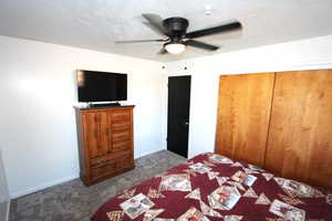 Bedroom with dark carpet, ceiling fan, a closet, and baseboards