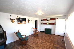 Unfurnished room featuring wood finished floors, a textured ceiling, baseboards, and a wood stove