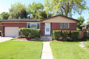 View of front facade featuring a garage, brick siding, and driveway