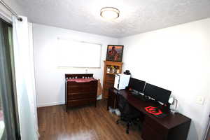Home office featuring a textured ceiling, dark wood finished floors, and baseboards