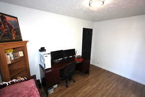 Home office featuring a textured ceiling, dark wood-style flooring, and baseboards