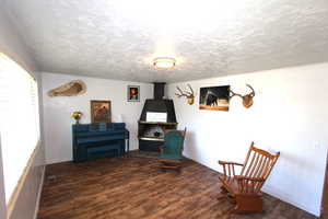 Sitting room with wood finished floors, a textured ceiling, and baseboards