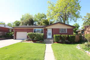 Ranch-style home featuring a garage, brick siding, and driveway