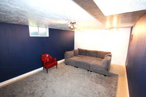 Living room featuring a textured ceiling, baseboards, and wood walls