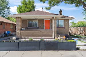 Bungalow featuring a chimney, brick siding, and roof with shingles