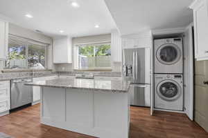 Basement/AUD kitchen featuring white cabinets, stainless steel appliances and granite countertops. Stackable washer and dryer are included