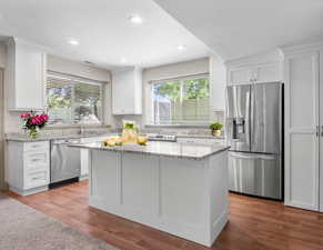 Kitchen featuring stainless steel appliances, plenty of natural light, white cabinets, a kitchen island, and recessed lighting