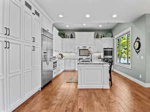 Beautifully updated kitchen with white cabinets, granite countertops, hickory hardwood floors and stainless steel appliances
