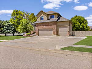 View of front facade featuring stucco siding, concrete driveway, a shingled roof, an attached garage, and brick siding